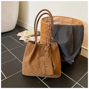 Detail of a brown frosted leather tote bag with a small square pouch in home setting