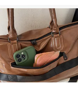Poche zippée avant d'un sac de voyage marron contenant un smartphone et un portefeuille