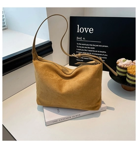 Detail shot of camel suede hobo bag with zip closure on a white table setting