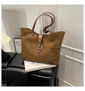 Braune Shopper-Tasche aus Wildleder mit Stern-Aufnäher und Metallschnalle auf einer Bank