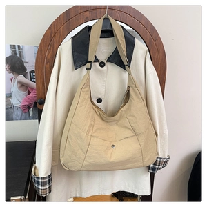 Détail du sac croissant en nylon kaki doté d'une poche frontale avec bouton-pression