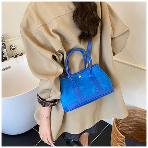 Dettaglio borsa a mano blu in pelle e camoscio abbinata a un outfit autunnale alla moda