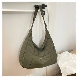 Détail du tissu en nylon matelassé vert olive et du bouton-pression métallique du sac bandoulière