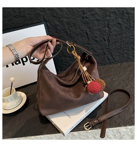 Detail of dark brown suede shoulder bag featuring ethnic-style plush ball charms