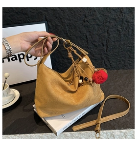 Detail of suede tote bag with decorative tassel and adjustable shoulder strap