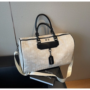 Detailed close-up of a woven texture travel bag with black handles and detachable strap