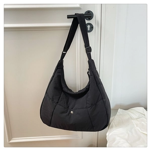 Détail d'un sac hobo en nylon matelassé noir avec bandoulière réglable sur une porte