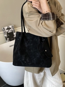 Large black frosted tote bag with side pouch worn by model in elegant urban setting