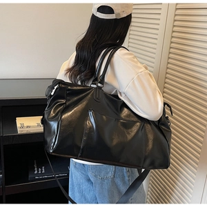 Grand sac de voyage en simili cuir noir porté par un mannequin montrant la taille