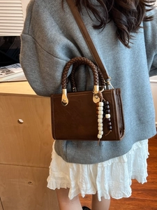 Vintage brown leather crossbody bag with woven handle and beaded charm on model