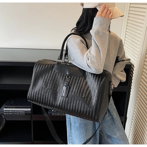 Detail of woven texture faux leather travel bag with sturdy handles and brand tag
