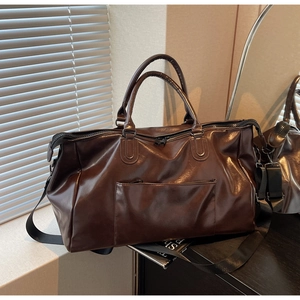 Détail du sac de voyage en similicuir marron avec bandoulière et double fermeture