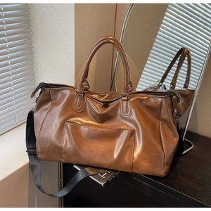 Détail du sac de voyage marron foncé en similicuir avec bandoulière réglable sous la lumière