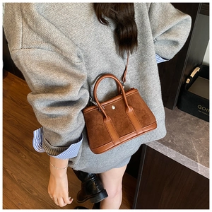 Brown suede leather bucket bag detail featuring circular metal lock and crossbody strap