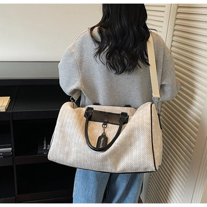 Detailed back view of a beige herringbone travel bag with black faux leather trim and strap