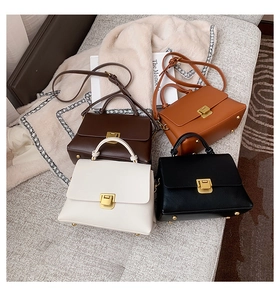 Top view of vintage leather handbags in four colors with gold metal locks on a soft rug