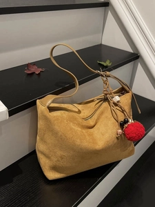 Brown suede dumpling tote bag with bohemian tassels on a staircase with autumn leaves