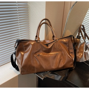 Détail du sac de voyage en similicuir marron avec sangle réglable et finition mate