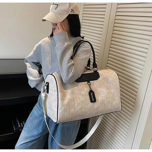 Detail of travel tote bag featuring woven texture and adjustable canvas shoulder strap