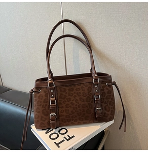 Detail of suede leopard print tote bag with brown leather straps and silver buckle accents
