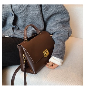 Detail of vintage dark brown leather crossbody bag with elegant gold square metal clasp