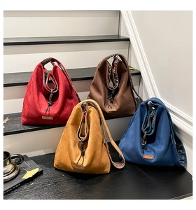 Close-up of four suede tote bags in various colors with decorative floral linings and drawstrings