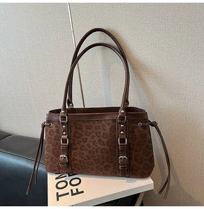 Detail of leopard print suede tote bag with dark brown leather trim and silver buckles