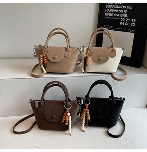 Detail of four matte leather handbags in khaki and coffee with colorful wooden bead charms