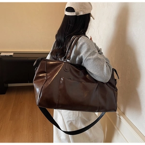 Détail d'un grand sac de voyage en cuir PU marron foncé avec poche avant et bandoulière