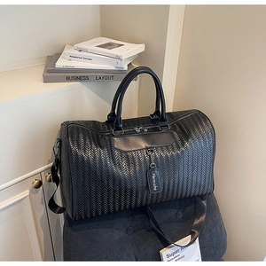 Detail of black leather travel bag featuring premium V-shaped woven texture and hardware