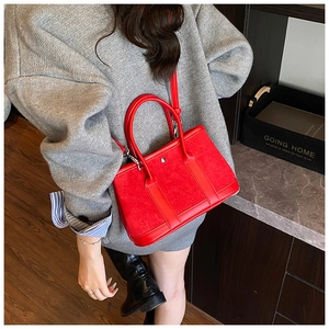 Close-up of a red leather bucket bag featuring mixed textures and a chic metal stud