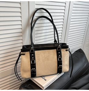 Detail of vintage beige suede tote bag with black leather trim and silver metal buckles