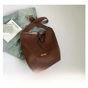 Detail view of large brown suede tote bag with leopard print lining and drawstring closure