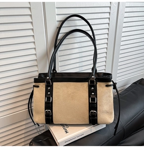 Detail of beige suede tote bag with black leather straps and metal buckle accents