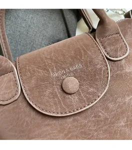 Close-up of brown textured leather shoulder bag featuring embossed branding and flap detail