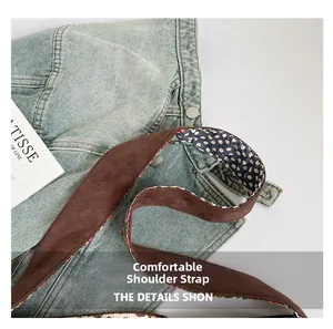 Detail of a brown suede shoulder strap with polka dot lining on denim bag