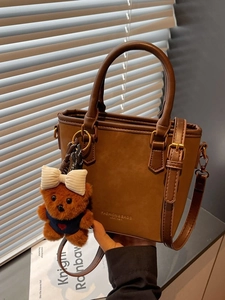 Vintage brown leather bucket bag with teddy bear pendant and adjustable strap