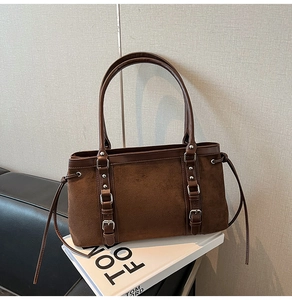 Detailed macro view of brown suede tote bag with leather straps and metallic buckle hardware