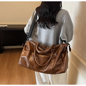 Grand sac de voyage marron brillant avec doubles poignées et bandoulière noire amovible