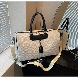 Detail of white woven travel bag with black leather handles and durable bottom studs