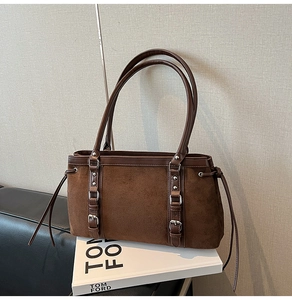 Detail of dark brown faux suede shoulder bag with buckle straps and drawstring sides