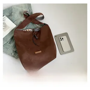 Detail of brown suede tote bag with leopard print lining and drawstring closure
