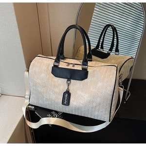 Close-up of beige woven texture travel bag with black PU handles and branding tag