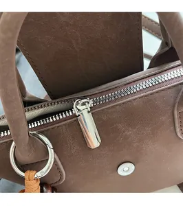 Close-up of silver metal zipper and hardware on a textured brown leather handbag