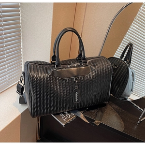 Detail of black woven texture on travel bag with leather tag and nylon strap