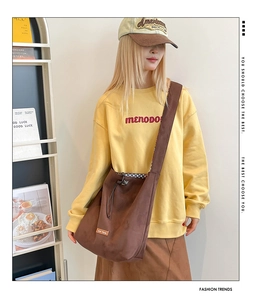 Detail of dark brown faux suede tote bag featuring a drawstring closure and leather logo patch
