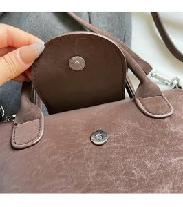 Detail showing the magnetic buckle closure on a brown vintage textured shoulder bag