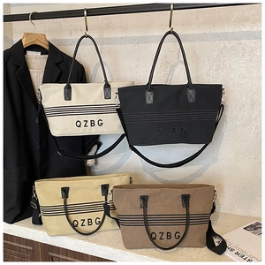 Detail view of canvas tote bags in cream, black, yellow, and khaki with QZBG embroidery