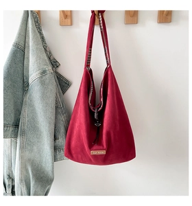 Detail of red tote bag featuring our fave leather tag and plaid lining on a hook