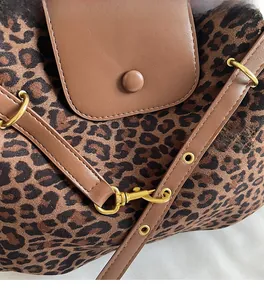 Close-up of leopard print suede bag with brown leather strap and gold hardware